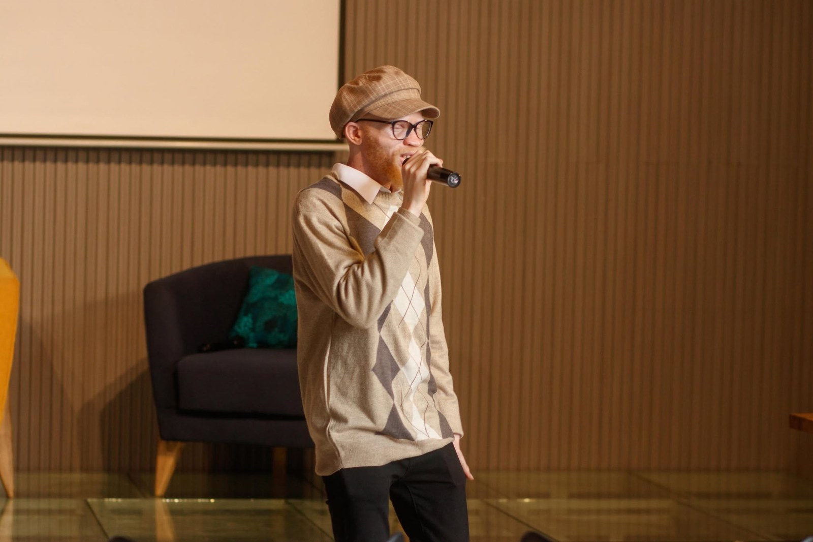 A poet with albinism performing on stage with a microphone.